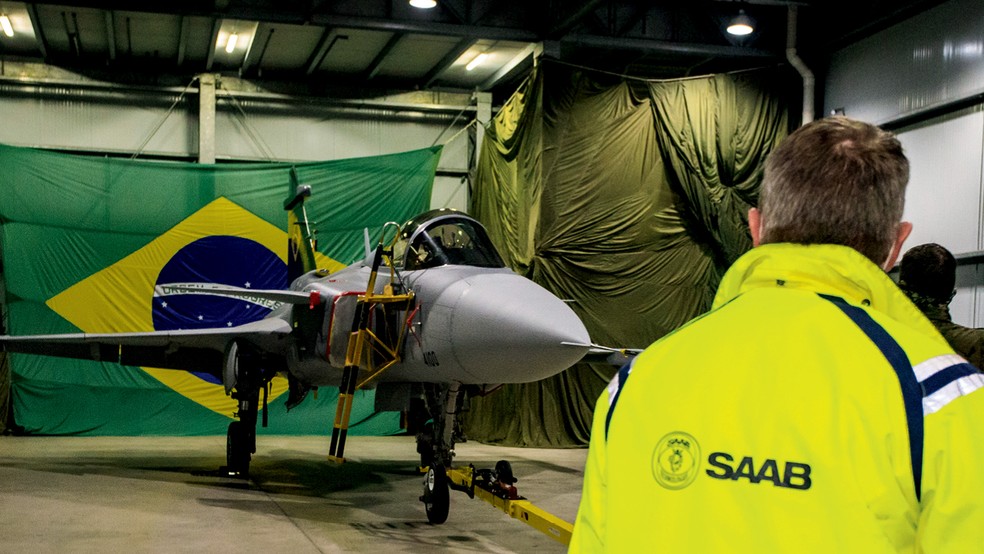 A montagem de um avião militar é cercada de segredos, daí a lona no fundo escondendo parte da fábrica — Foto: Divulgação