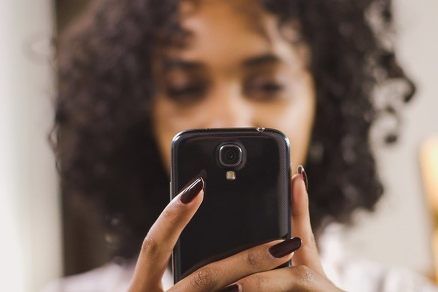 Mulher consulta celular (Foto: Shopify)