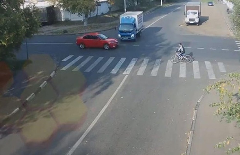 Vídeo registra o momento em que o caminhão bate no carro vermelho, quase atinge o ciclista e capota em seguida (Foto: Reprodução) — Foto: Auto Esporte
