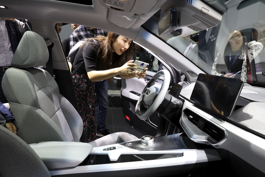 Mulher fotografa o interior de sedã da Geometry, marca de elétricos da montadora chinesa Geely — Foto: Ng Han Guan/AP
