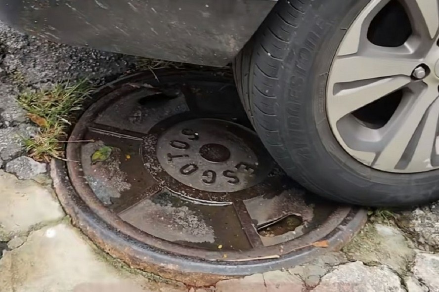 Carro estacionado em cima de bueiro