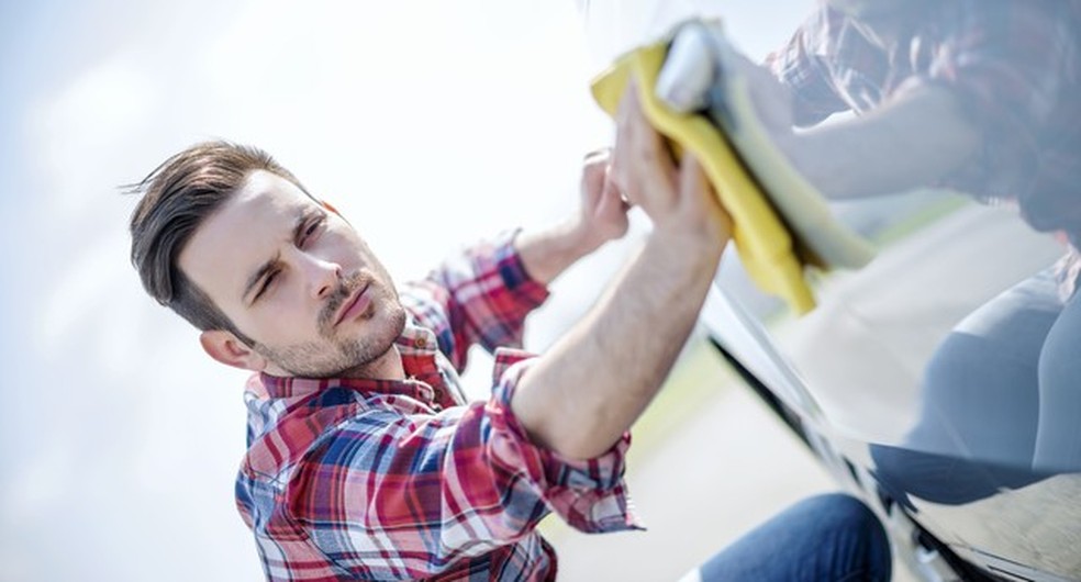 Young man cleaning his car outdoors.Man with a microfiber wipe the car polishing (Foto: Getty Images/iStockphoto) — Foto: Auto Esporte